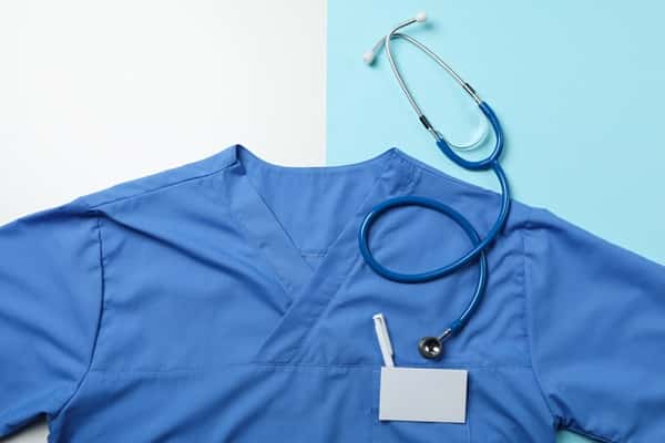 Blouse médicale bleue avec stéthoscope et badge sur fond bleu et blanc, conçue pour les professionnels de la santé