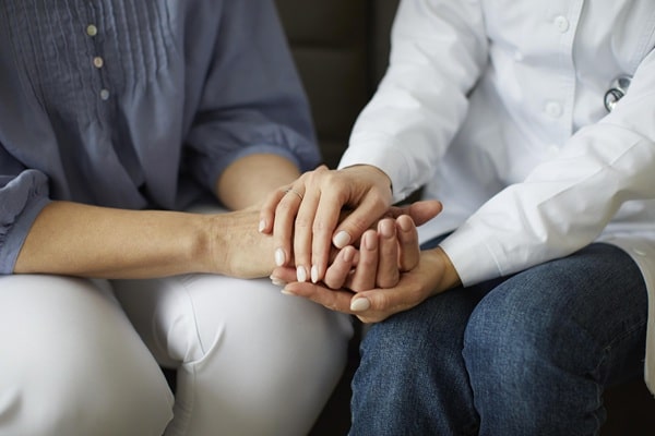 Gros plan sur les mains d’un professionnel de santé tenant celles d’un patient, symbolisant l’accompagnement et le soutien en psychothérapie libérale.