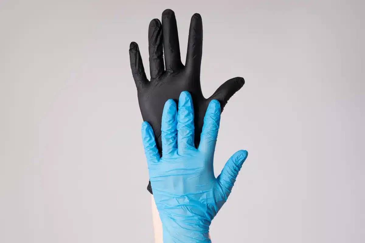 Deux mains portant des gants en vinyle, l'une en bleu et l'autre en noir, symbolisant la diversité du matériel médical